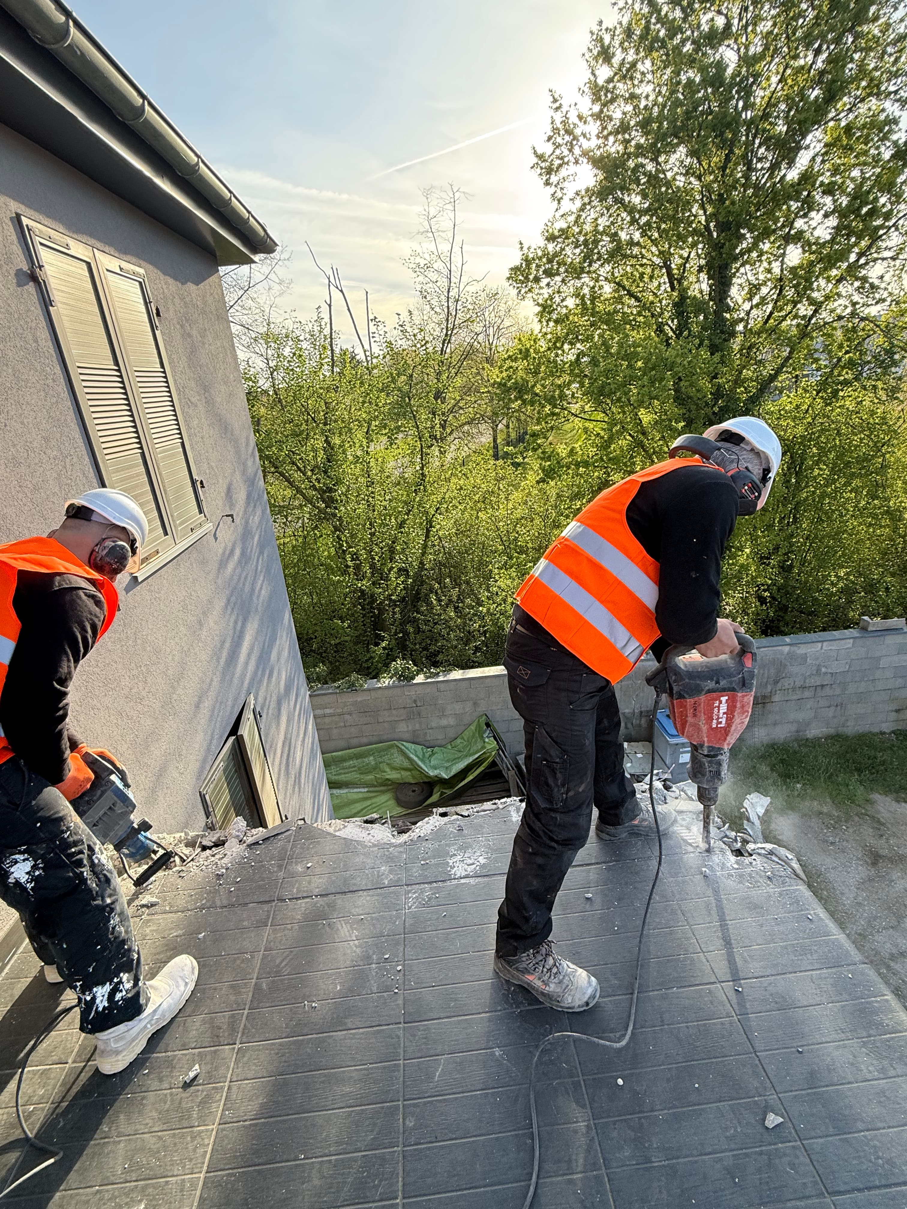 Piquage du carrelage et du plancher haut au marteau-piqueur, équipements de protection complets.
